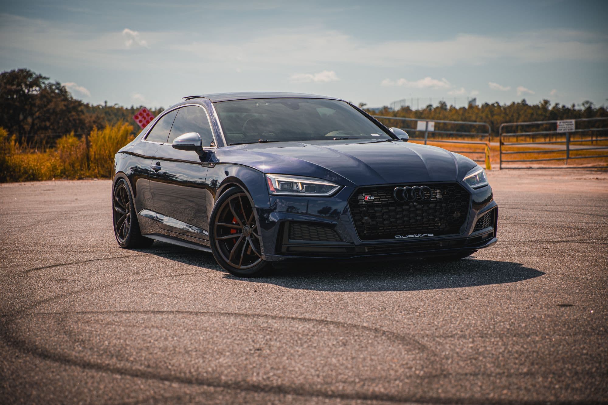 A navy blue B9 Audi S5 on bronze wheels parked on a sunlit lot